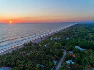 Aerial view of sunset over La Libertad beach in El Salvador, showcasing palm trees and serene waves