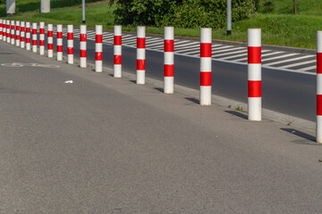 Row of red and white traffic bollards separating road lanes, providing safety and traffic control...