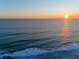 Sunset over ocean shore showcasing the tranquil waves and vibrant colors of the coast