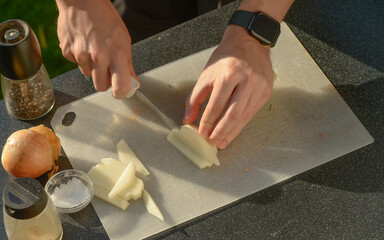 a man's hands cutting raw potatoes into long slices with a knife.a man preparing potatoes cutting into long slices