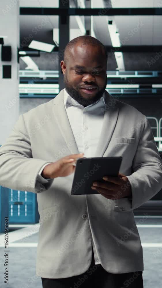 Poster vertical video smiling admin using tablet in in data center maintaining infrastructure for workloads
