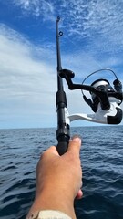 Woman hand wrist holding fishing rod with sea background.Blue sky with clouds.Scotland