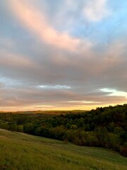 Sunset. Warm sunlight on green hills and tree crowns.