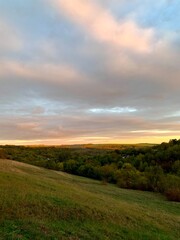 Sunset. Warm sunlight on green hills and tree crowns.