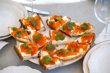 Colorful caviar sandwich topped with fresh herbs served on a decorative platter for a festive gathering