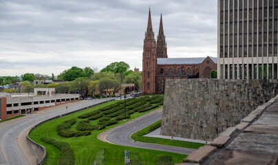 Views of historic cathedral with spires and landscaped greenery in urban setting during cloudy day