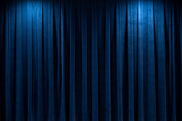 Dark blue theater curtains illuminated by stage lights create a dramatic backdrop
