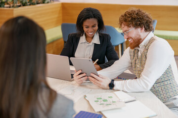 A diverse team is collaborating on an innovative project using various digital devices in a modern...