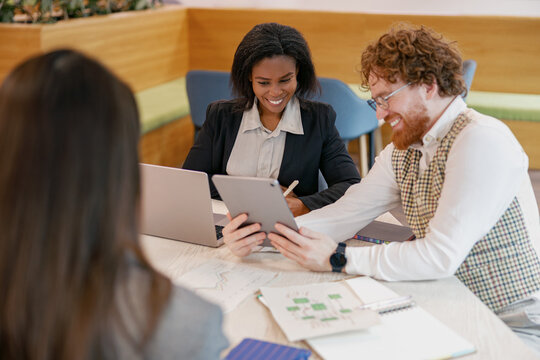 A diverse team is collaborating on an innovative project using various digital devices in a modern workspace - Powered by Adobe