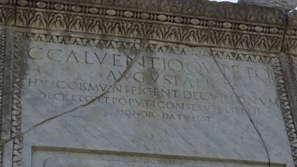 Pompeii, Italy – 8 January 2025. At the Necropolis of Porta Ercolano in Pompeii, a marble tomb bears a Latin inscription honoring C. Calventius Quietus, bordered by carved vegetal patterns.