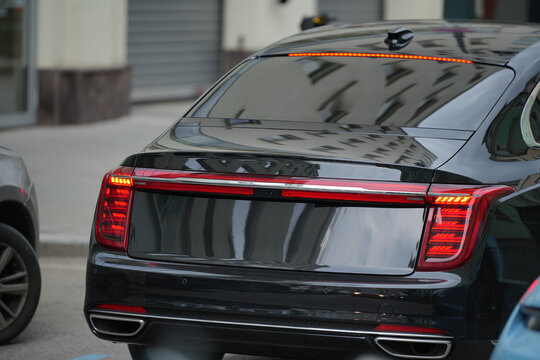 Close-up of the rear part of a luxury black Hongqi H9 car on a city street, showcasing stylish design and brand details