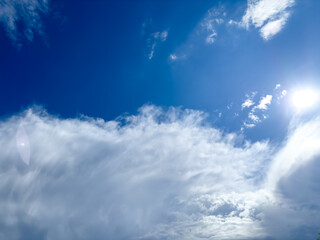 Bright blue sky with white clouds and sun flare – clear summer weather background