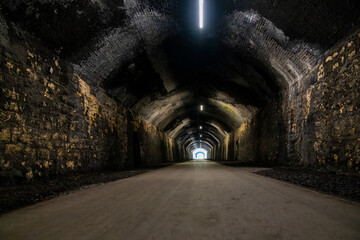 Naklejka premium Light at the end of tunnel illuminating old brick passage