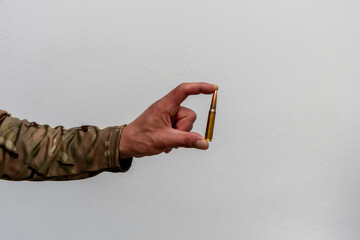 A single cartridge in the hand of a soldier. Minimalistic image conveying the theme of weaponry, war and the decisive shot.