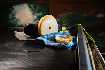 Equipment for polishing a car is placed on the hood, as the tools await use under bright sunlight...