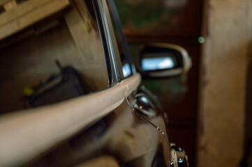 A car receiving polishing attention inside a garage, highlighting gleaming surfaces and reflections...