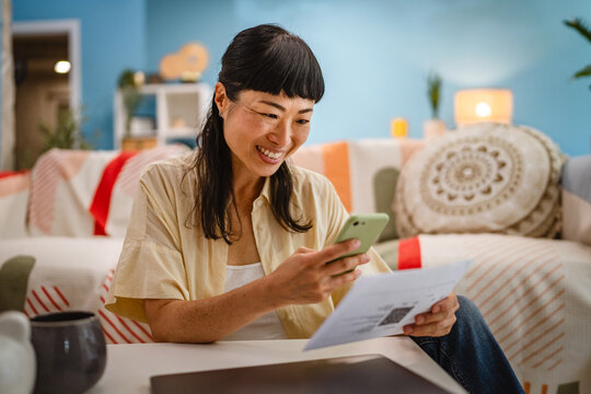 Japanese mature woman use mobile phone to pay bills,