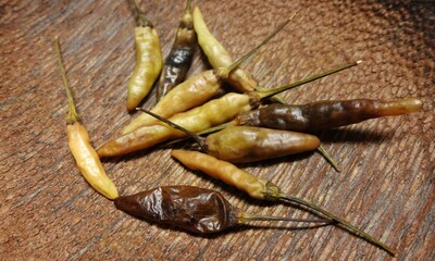 A bunch of rotten chilies on a wooden board. Uneaten chilies.