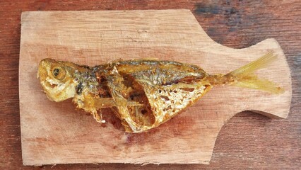 Flat lay angel of fresh fried fish served on a cutting board. Selar fish or Selaroides leptolepis for consumption.