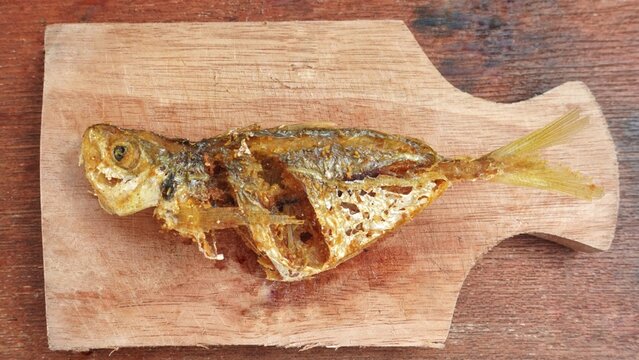 Flat lay angel of fresh fried fish served on a cutting board. Selar fish or Selaroides leptolepis for consumption.