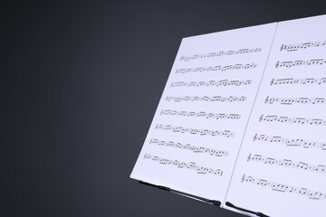 Note stand with music sheets on grey background, closeup. Space for text