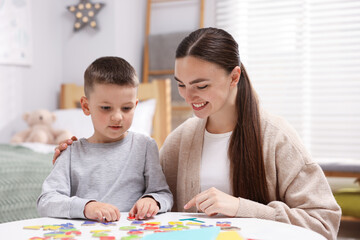 Fototapeta premium Dyslexia. Mother and her son learning letters at table indoors