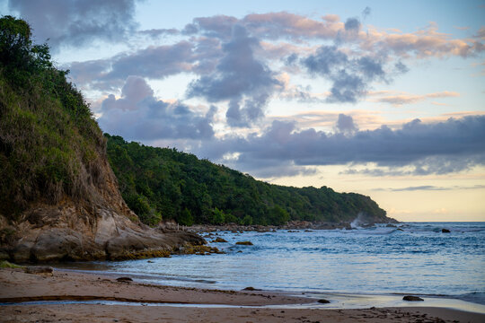 Sunset on the beach with rocky coastal cliffs.  - Powered by Adobe