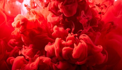Obraz premium A macro photograph captures vibrant red dye dispersing and mingling in liquid, creating cloud forms.