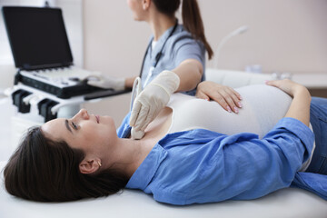 Sonographer conducting ultrasound examination of woman's thyroid gland in clinic, closeup