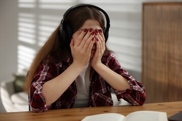 Stressed teenage girl studying at desk indoors