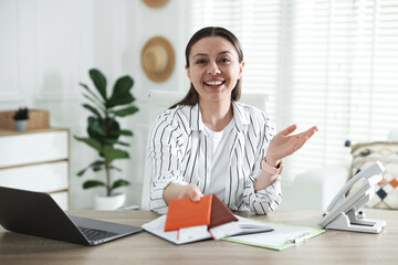 Travel agent with passports and tickets at wooden table in office