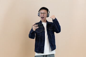 excited gamer with his headphones and mobile phone in studio background