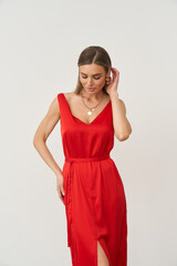 Stylish woman in a red dress posing confidently in a bright indoor studio setting