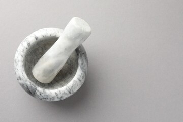 Marble mortar and pestle on light grey background, top view. Space for text