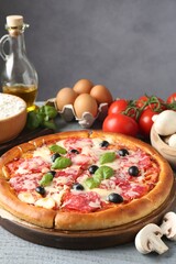 Tasty pizza and ingredients on grey wooden table, closeup