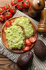 Delicious sandwiches with avocado, sesame seeds, tomatoes and spices on wooden table, flat lay