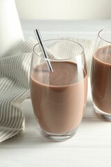 Tasty chocolate milk in glasses on white wooden table, closeup