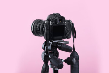 Modern professional video camera on pink background, closeup