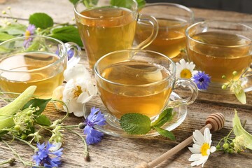 Aromatic herbal tea in glass cups, mint and flowers on wooden table, closeup