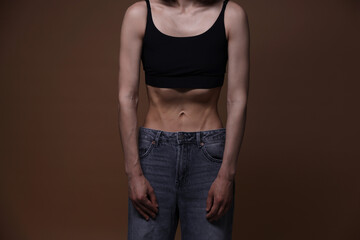 Woman suffering from anorexia on brown background, closeup