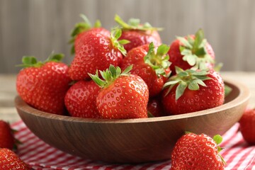 Fresh ripe strawberries in bowl on wooden table, closeup
