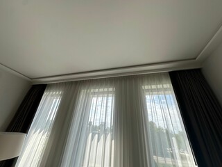 Beautiful curtains hanging on cornice near window indoors, low angle view