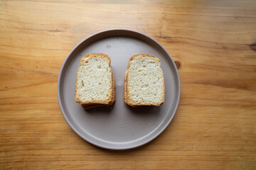 Close-up of two crispy toasted bread slices on a clean white plate. The texture and color highlight...