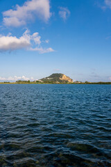Fototapeta premium A tranquil view of Capo Miseno in Bacoli, Italy, seen from the calm blue waters under a bright summer sky