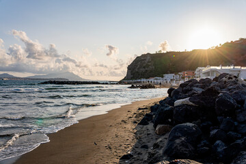 Warm sunset light touches the sandy shore of Miseno Beach in Bacoli, Italy. Gentle waves, seaside...