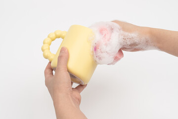 Hand Washing Yellow Mug with Soapy Sponge – Kitchen Cleaning Concept