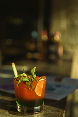Vibrant red cocktail in a glass decorated with fresh lime mint and straws perfectly styled on a table for summer refreshment