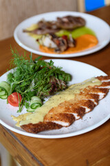 Tender meat served with creamy mashed potatoes and fresh salad on a plate for a satisfying hotel dining experience