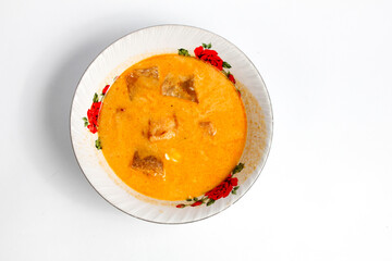 fried sambal dish filled with potatoes mixed with coconut milk and spicy krecek served in a ceramic bowl ,isolated on white background