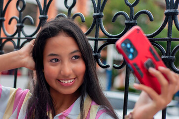 Young latin woman taking a selfie with smartphone and fixing her hair